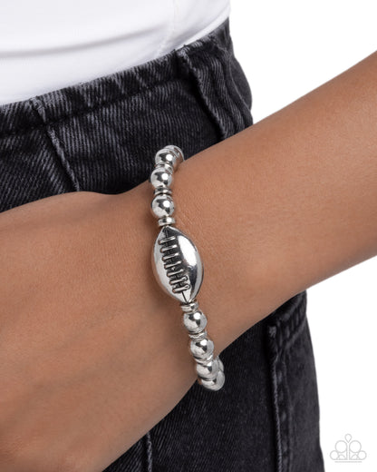 Silver beaded bracelet on a wrist with a white background