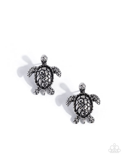 Pair of turtle-shaped earrings with intricate detailing on a white background
