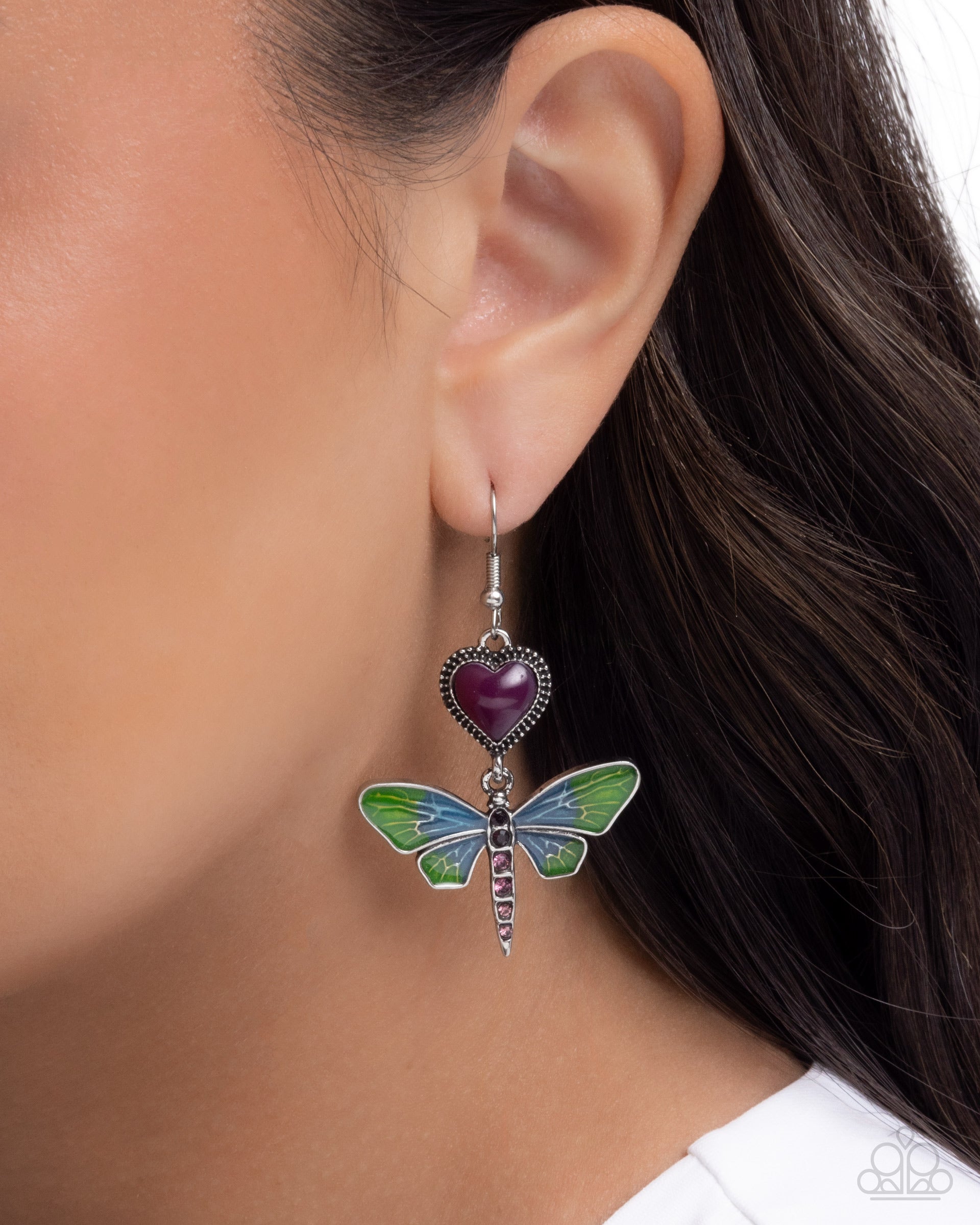 Earring with heart and dragonfly design worn by a person