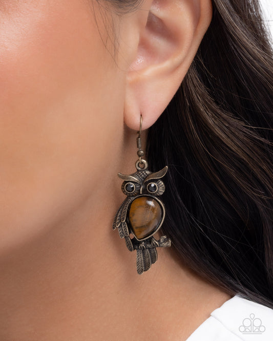 Close-up of an owl-shaped earring worn by a person with dark hair.