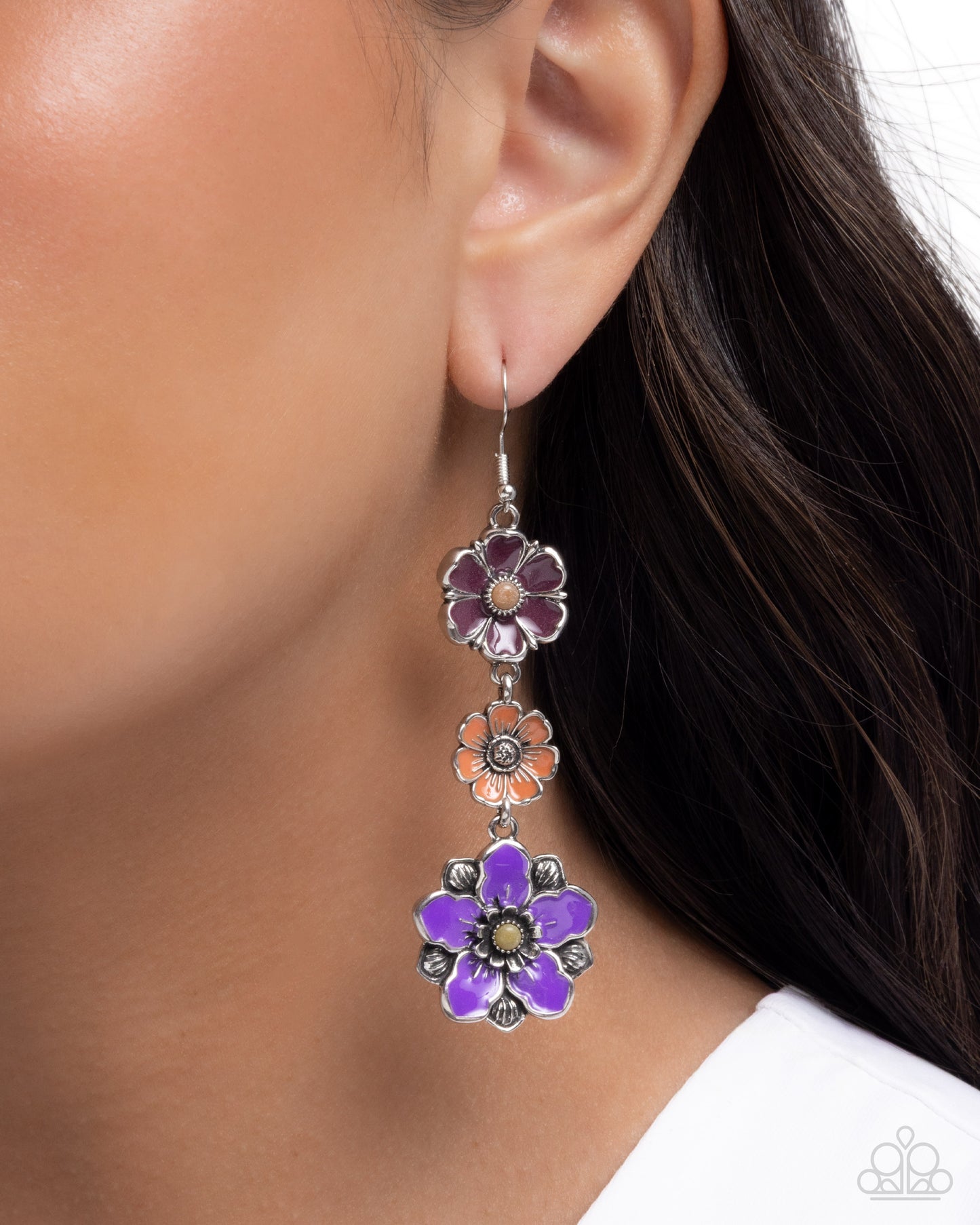 Floral earrings being worn on an ear with a blurred background