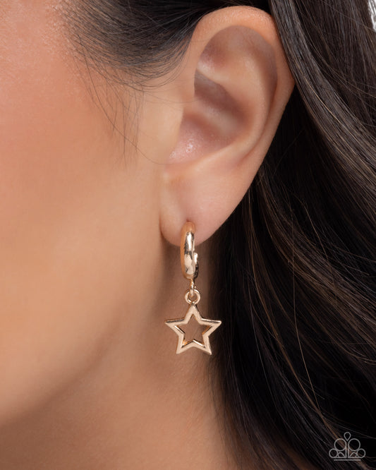 Gold star-shaped earring worn by a person with dark hair.