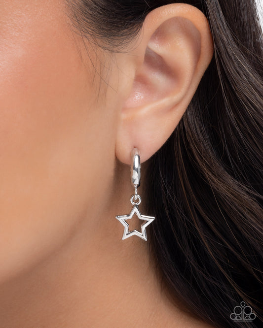 Silver star-shaped earring worn on an ear with dark hair.
