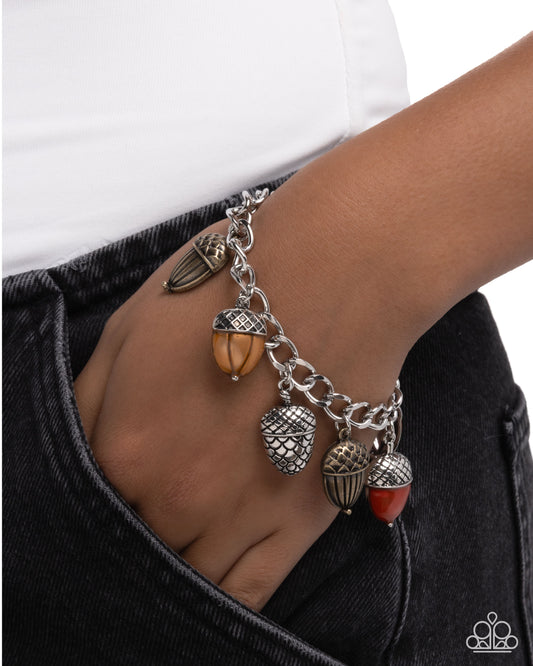 Silver bracelet with acorn charms on a wrist against a white background
