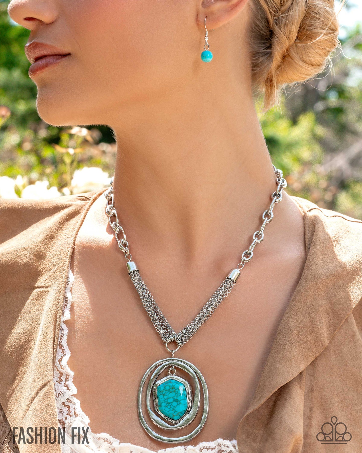 Woman wearing a turquoise pendant necklace and earrings with a blurred natural background