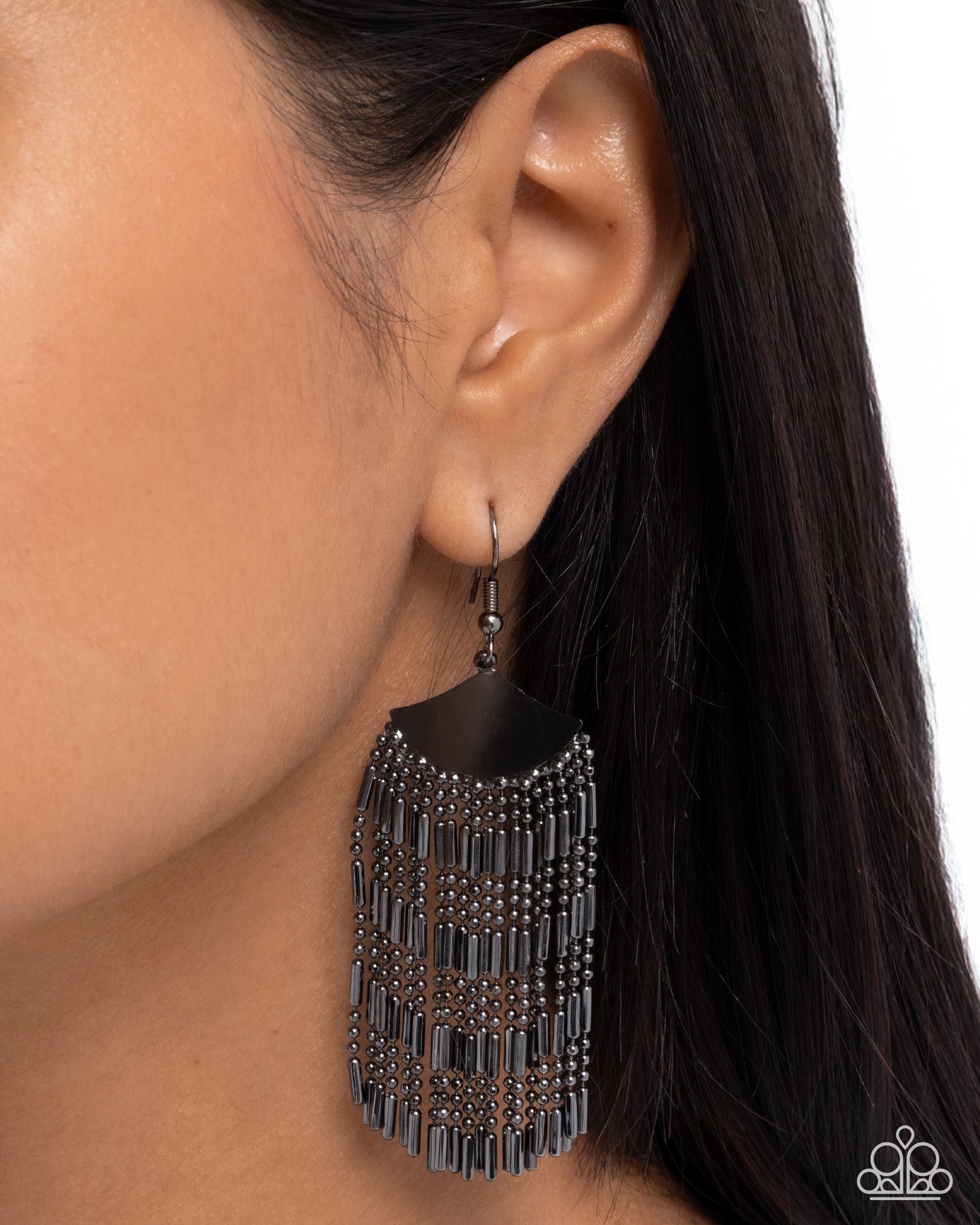 Black fringe earring worn by a person with dark hair on a white background