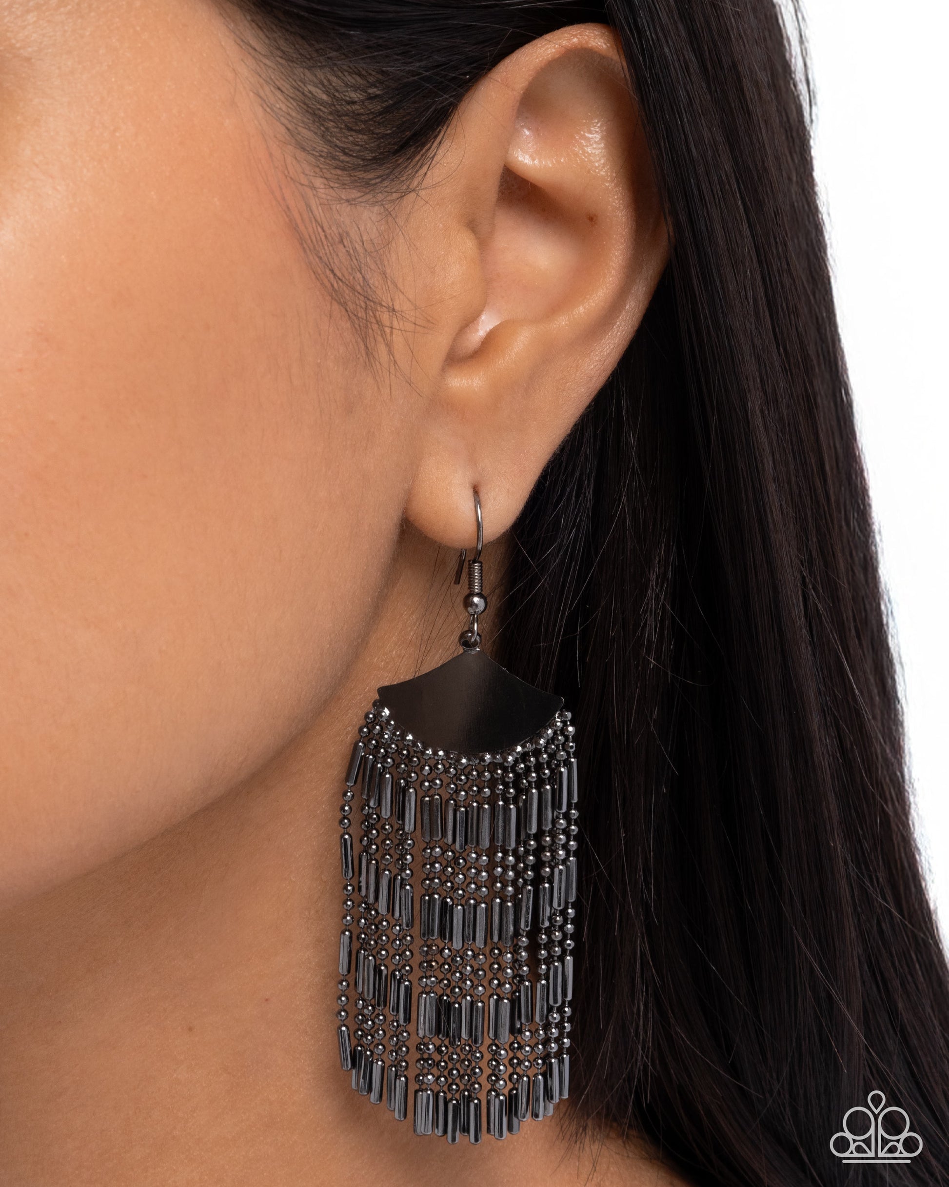 Black fringe earring worn by a person with dark hair on a white background
