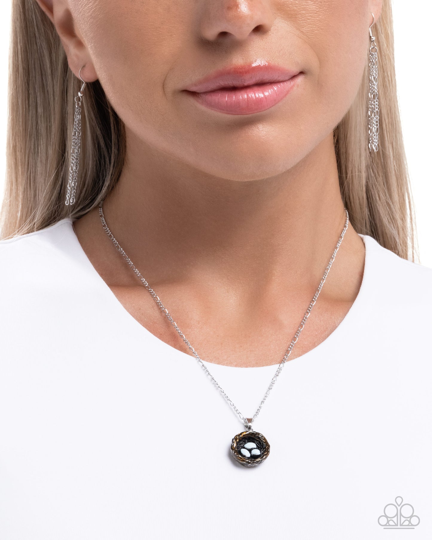 Woman wearing a silver necklace with a black pendant on a white background