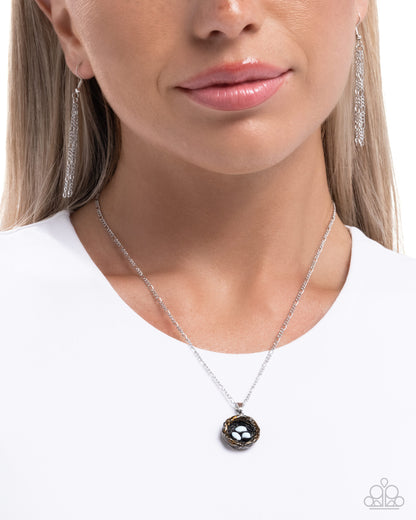 Woman wearing a silver necklace with a black pendant on a white background