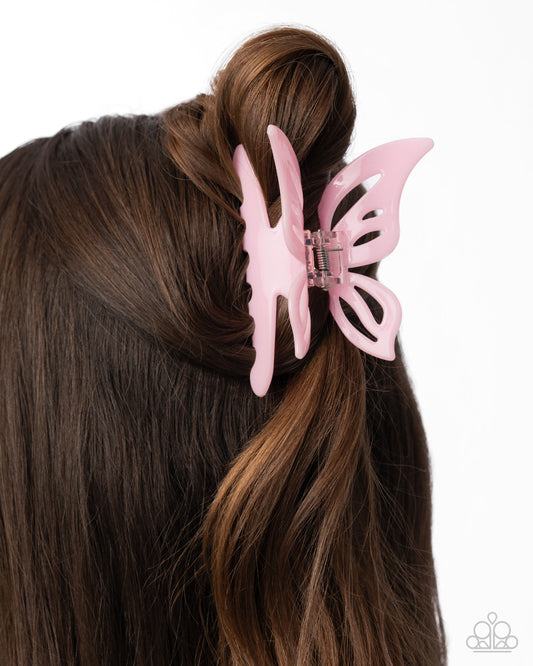 Pink butterfly hair clip in a brown hair bun on a white background