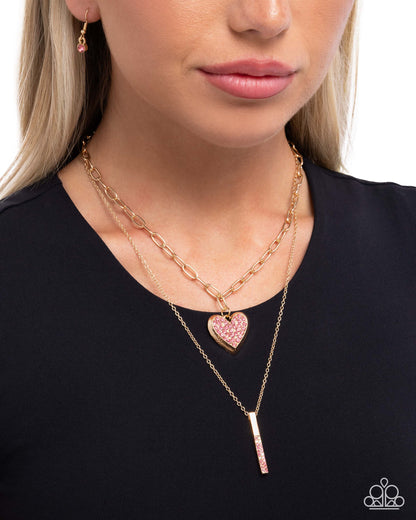 Woman wearing a gold necklace with a heart pendant on a plain background