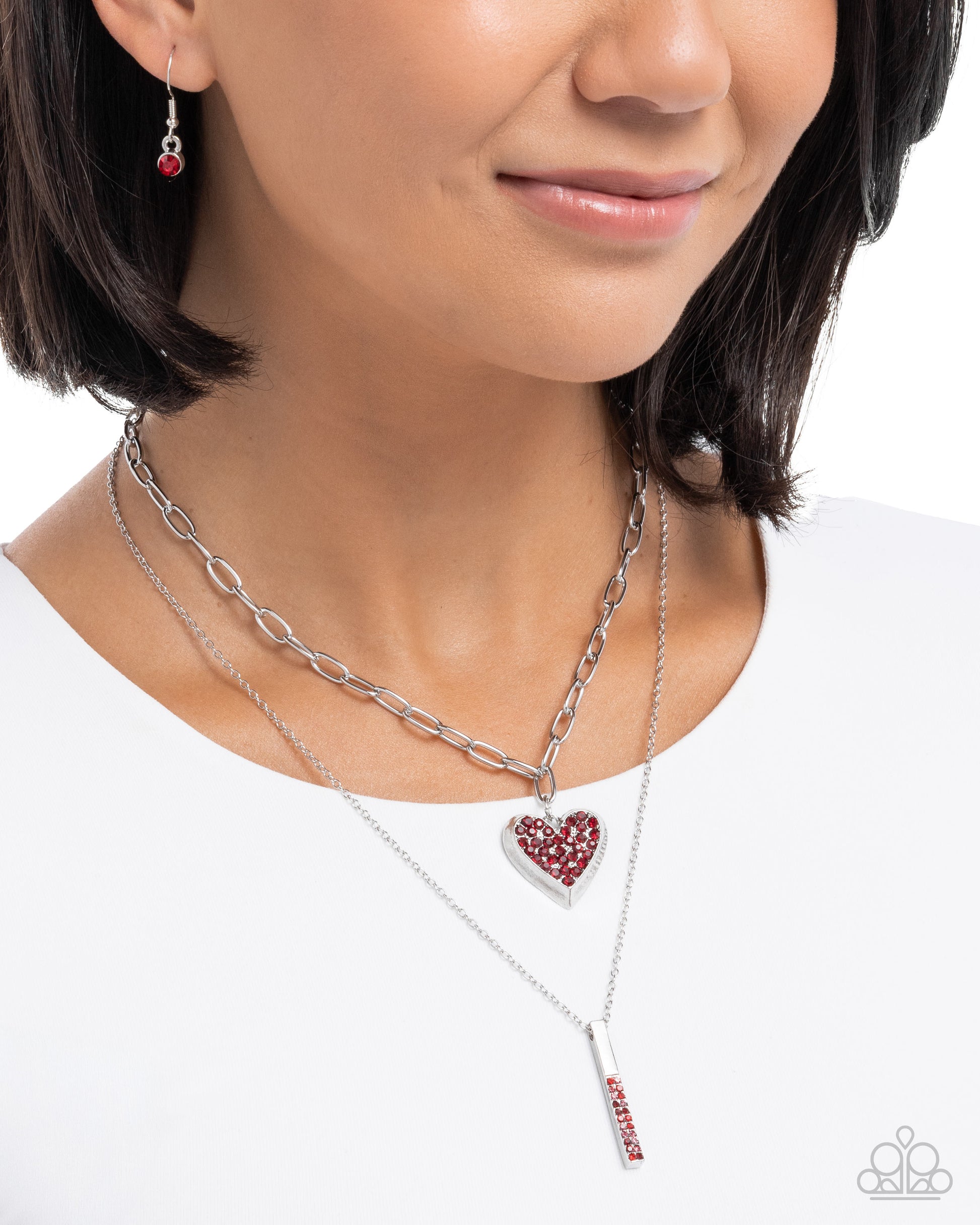 Close-up of a woman wearing multiple necklaces with heart and bar pendants on a white background