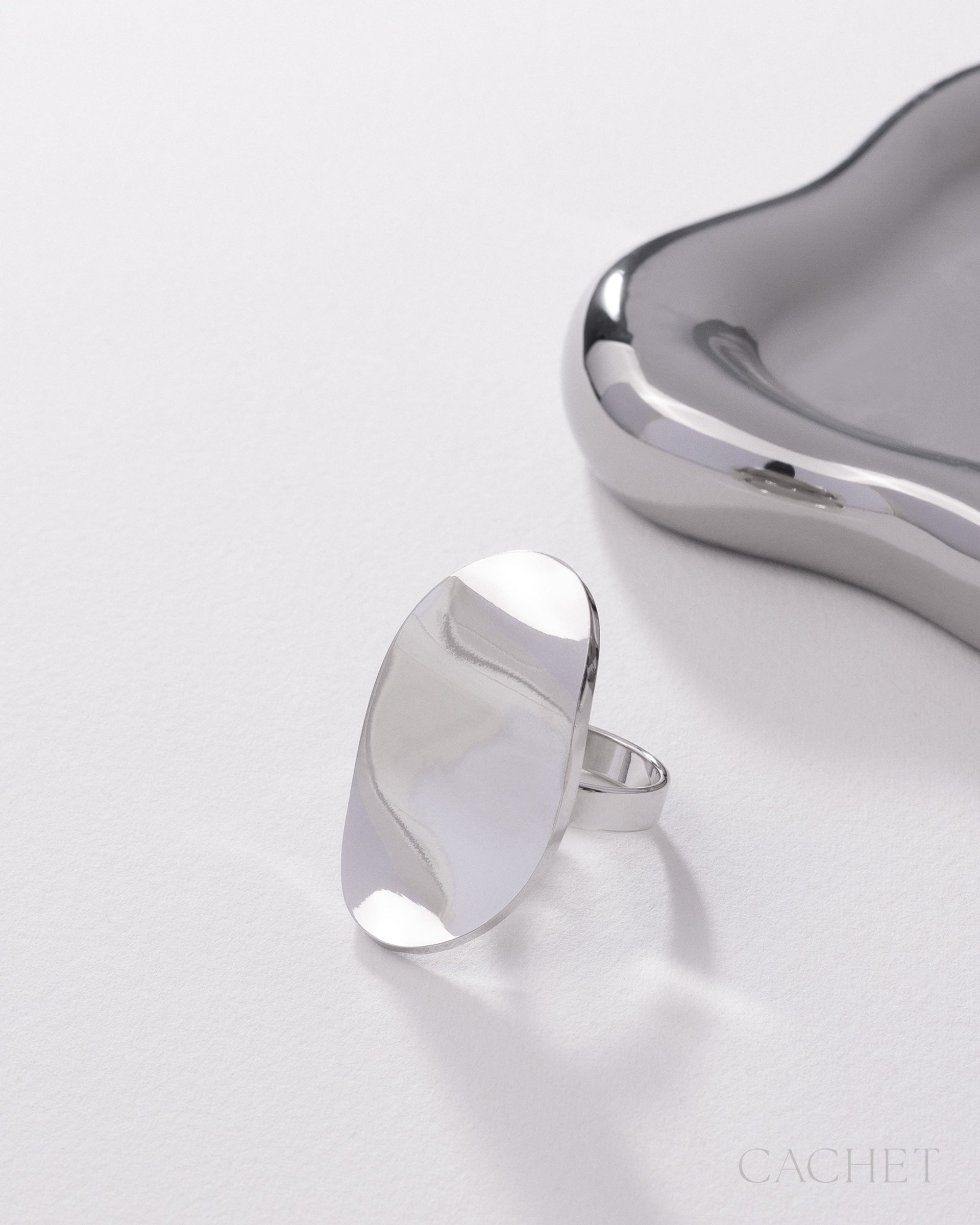 Silver ring on a white surface with 'Cachet' branding.