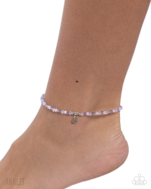 Ankle bracelet with small heart charm on a white background