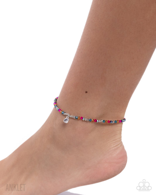 Colorful beaded anklet on a foot against a white background