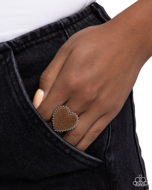 Heart-shaped ring on a hand with black pants