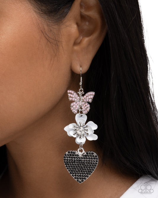 Earring with butterfly and heart design worn by a person