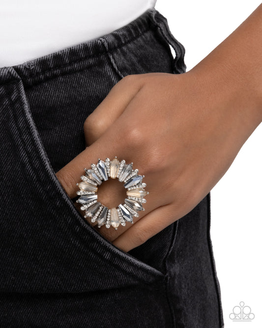 Close-up of a hand wearing a decorative ring with black pants on a white background