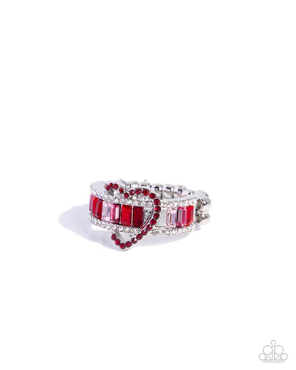 Heart-shaped ring with red gemstones and silver accents on a white background
