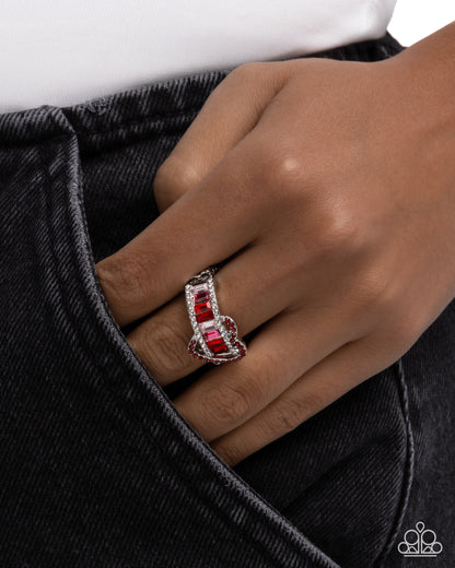 Close-up of a hand wearing a red and silver ring on a dark background