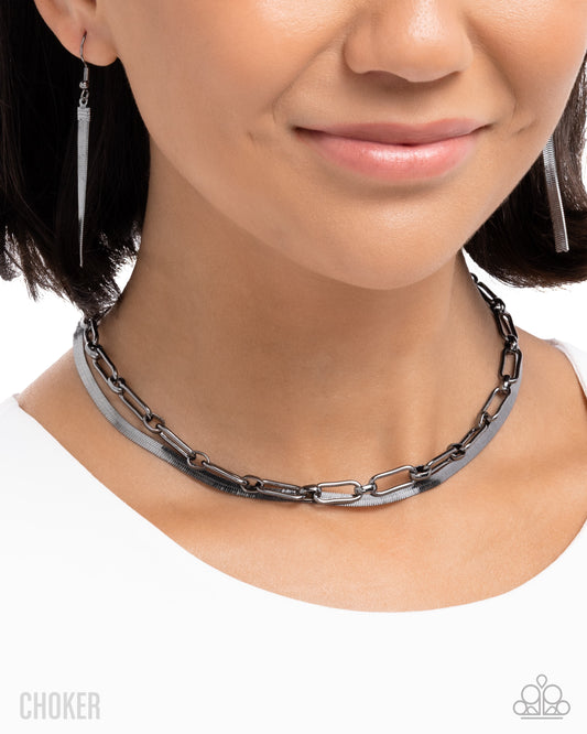 Person wearing a chain choker necklace with matching earrings on a white background