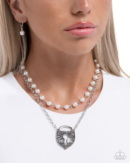 Pearl necklace with a silver lock pendant worn by a model on a white background