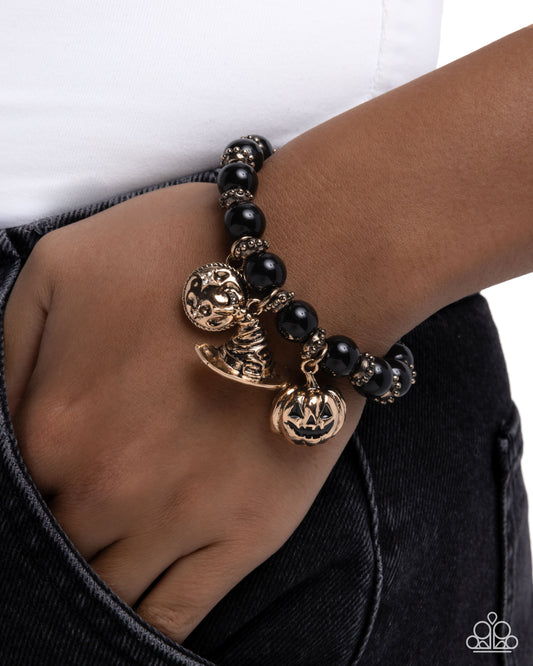 Black beaded bracelet with gold accents on a wrist against a white background