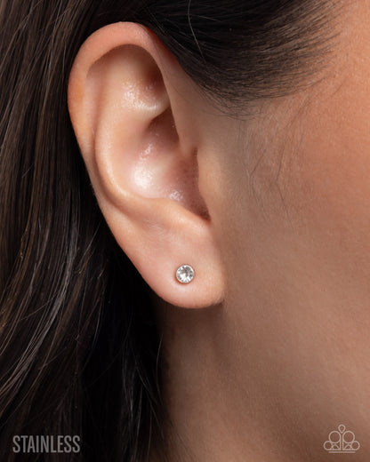 Close-up of an ear wearing a silver stud earring with 'Stainless' text below.