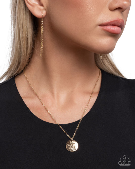 Close-up of a woman wearing a gold necklace and earrings on a plain background