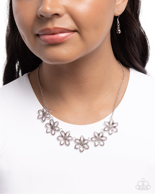 Necklace with floral designs worn by a model on a white background