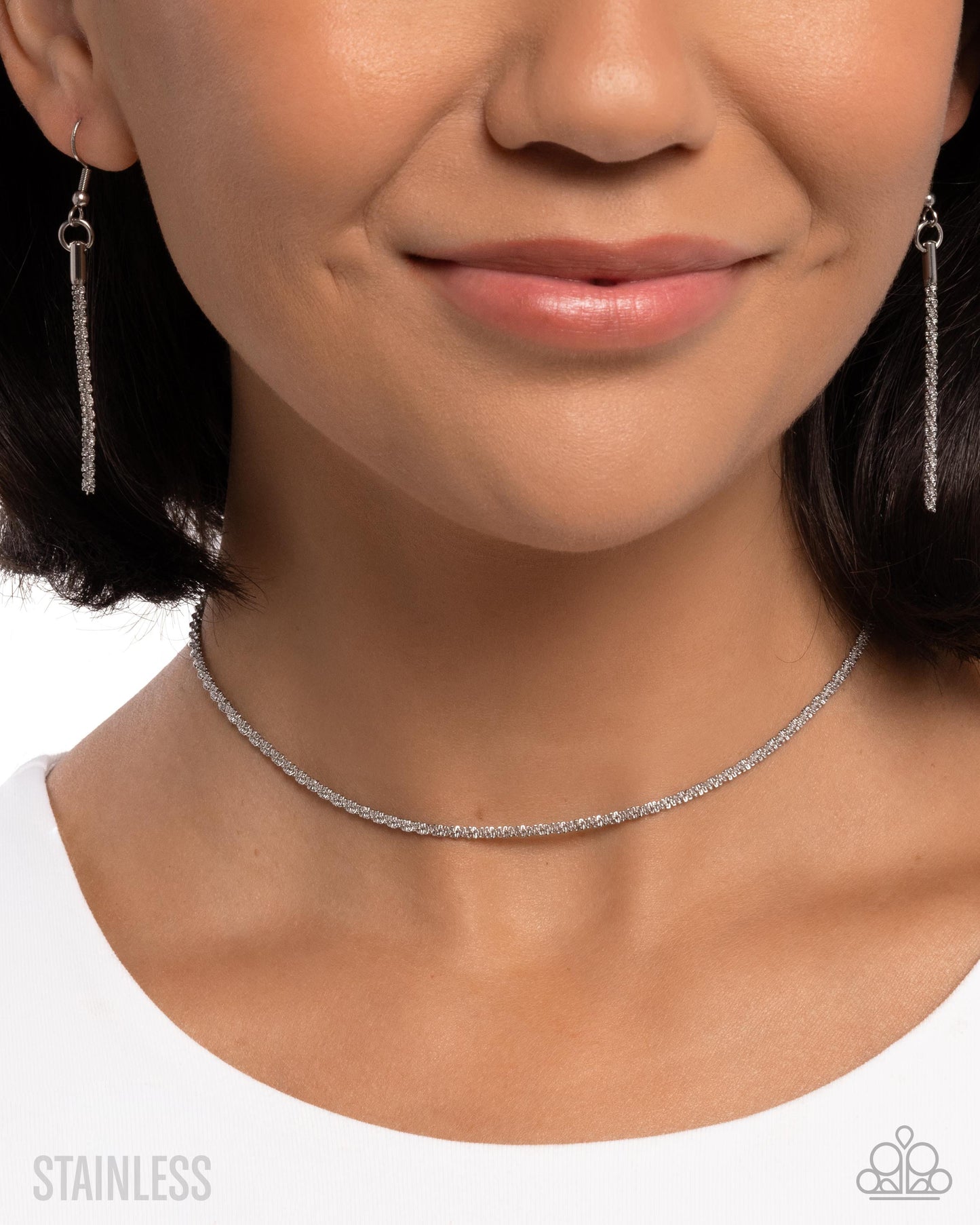 Close-up of a person wearing silver earrings and a choker necklace on a white background.