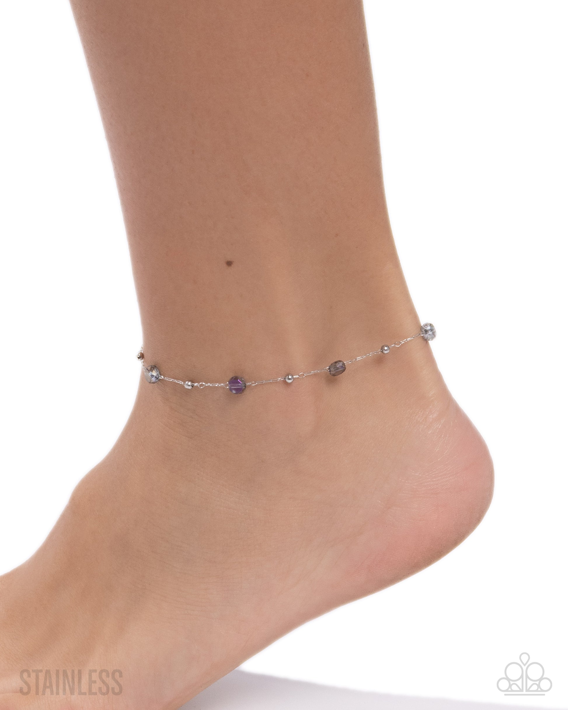 An anklet with small beads on a foot against a white background
