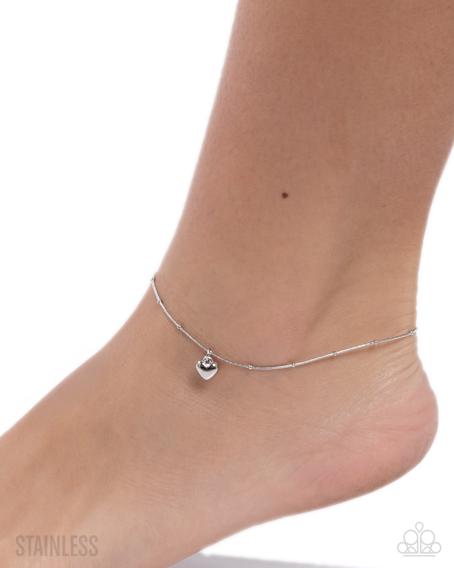 Silver anklet on a foot with a white background