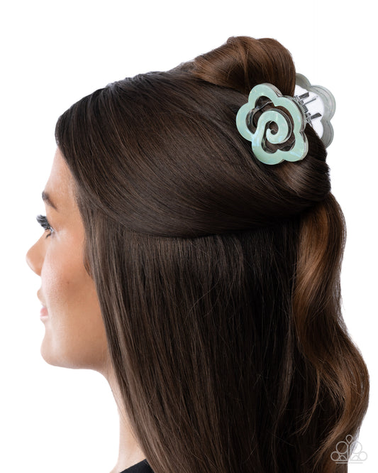 Woman with brown hair styled with a decorative hair clip on a white background