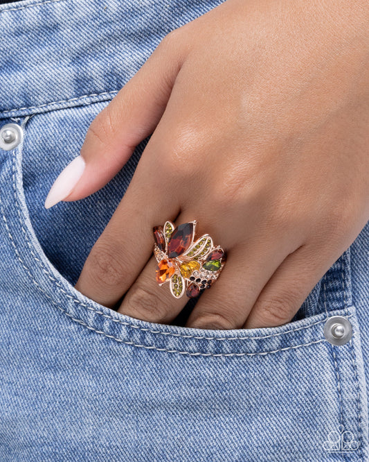 Hand wearing a colorful butterfly ring on denim fabric