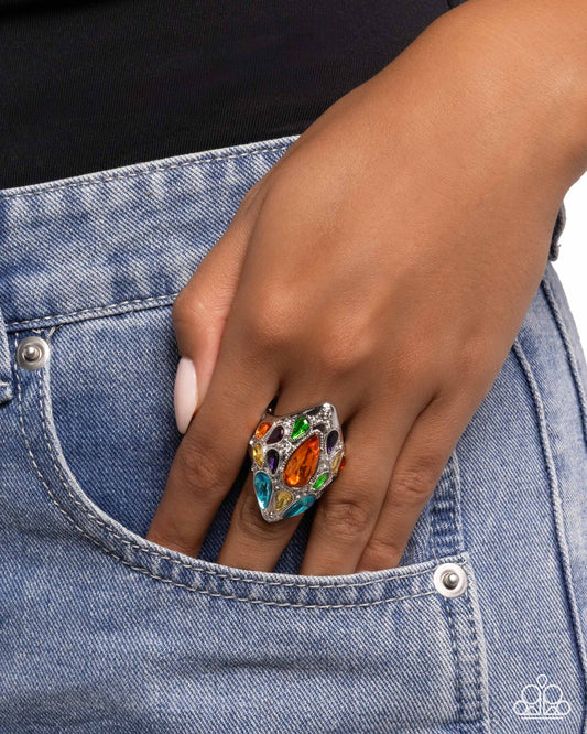 Hand wearing a colorful ring on a denim background