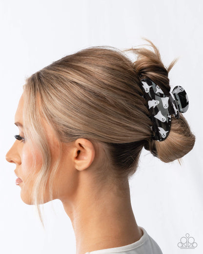 Woman with blonde hair styled in a bun with a black scrunchie featuring white paw prints.