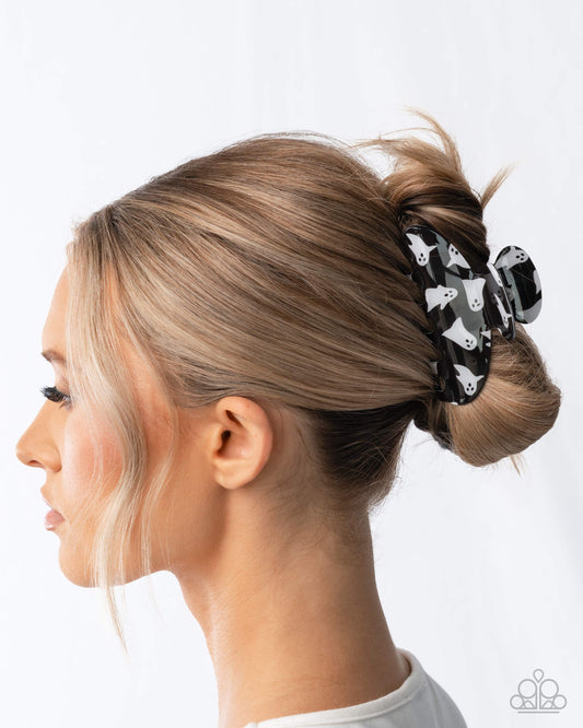 Woman with blonde hair styled in a bun with a black scrunchie featuring white paw prints.