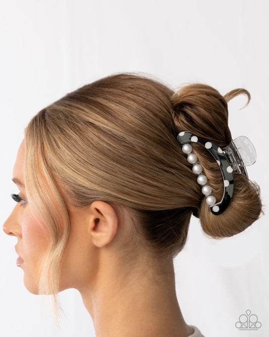 Woman with a styled bun using a hair clip with pearls on a white background