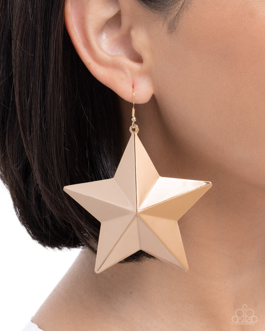 Gold star-shaped earring worn by a person with dark hair.
