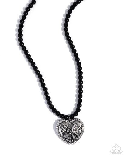 Black beaded necklace with a silver heart-shaped pendant on a white background