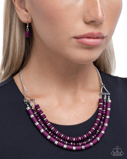 Purple beaded necklace with silver accents worn by a model on a white background