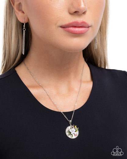 Woman wearing a silver necklace with a floral pendant on a plain background