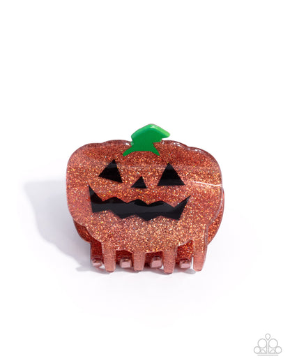 Pumpkin-shaped hair comb with glittery texture on a white background
