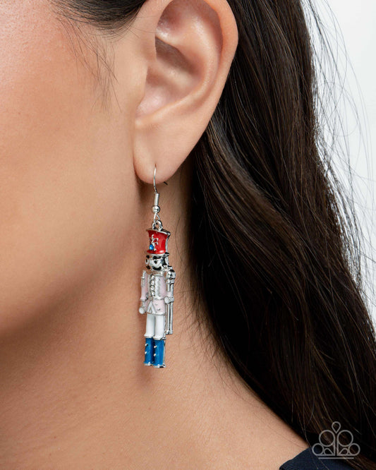 Close-up of an ear wearing a decorative earring with a nutcracker design.