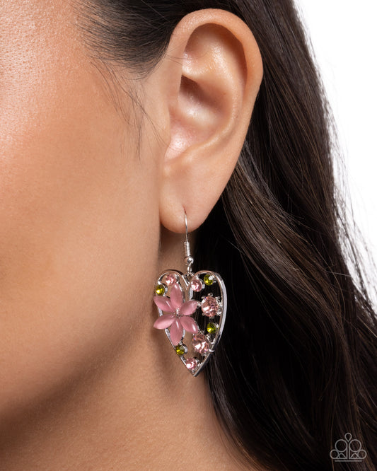 Heart-shaped earring with pink floral design worn by a person