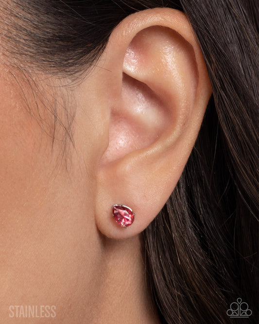 Close-up of an ear wearing a pink and silver earring with 'Stainless' text.