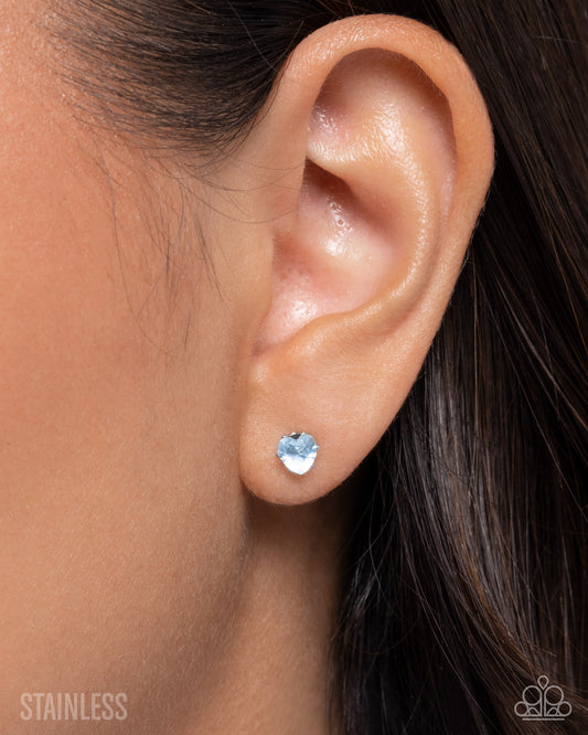 Close-up of an ear wearing a silver heart-shaped stud earring with 'Stainless' text.
