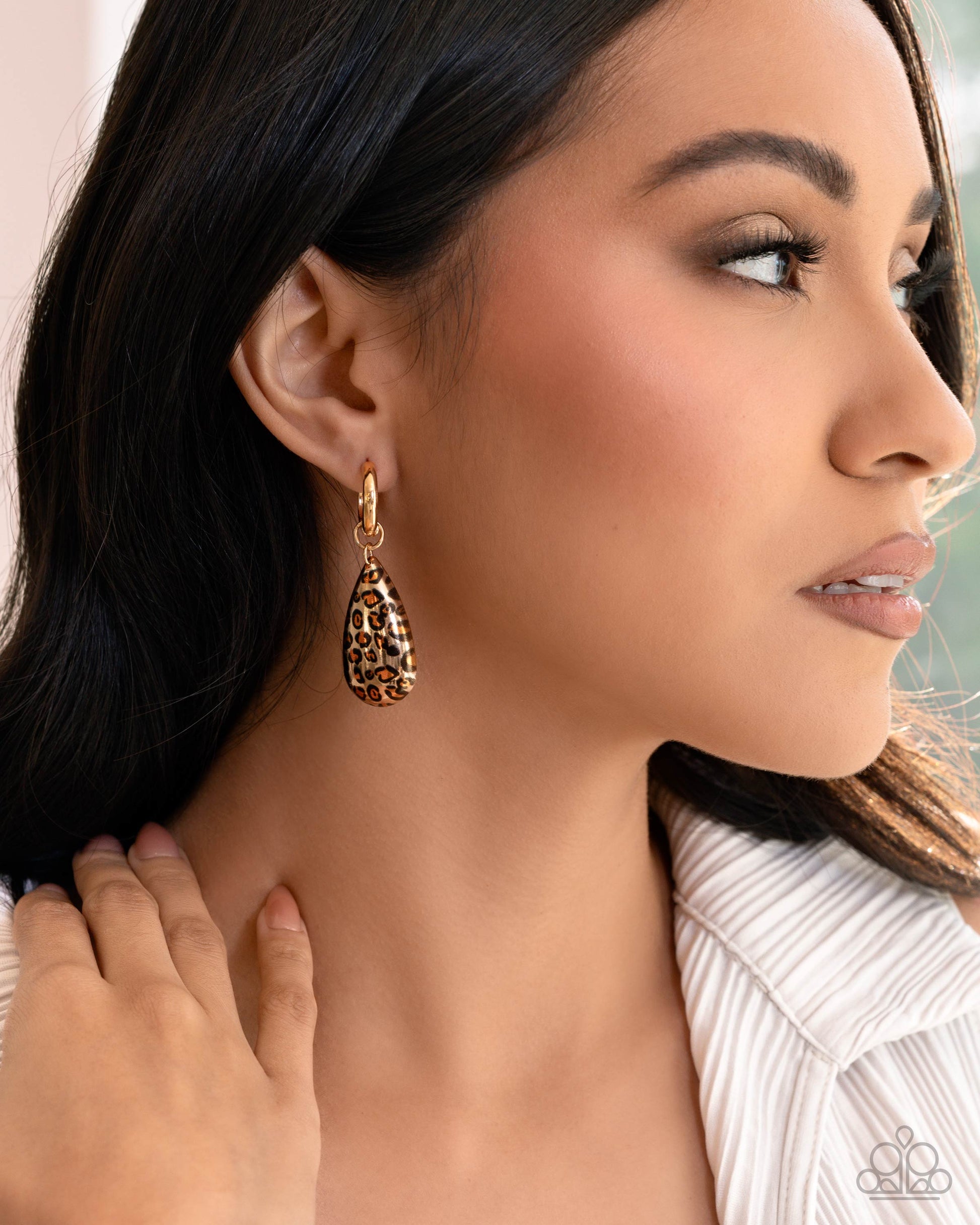 Woman wearing a gold earring with a leopard print design