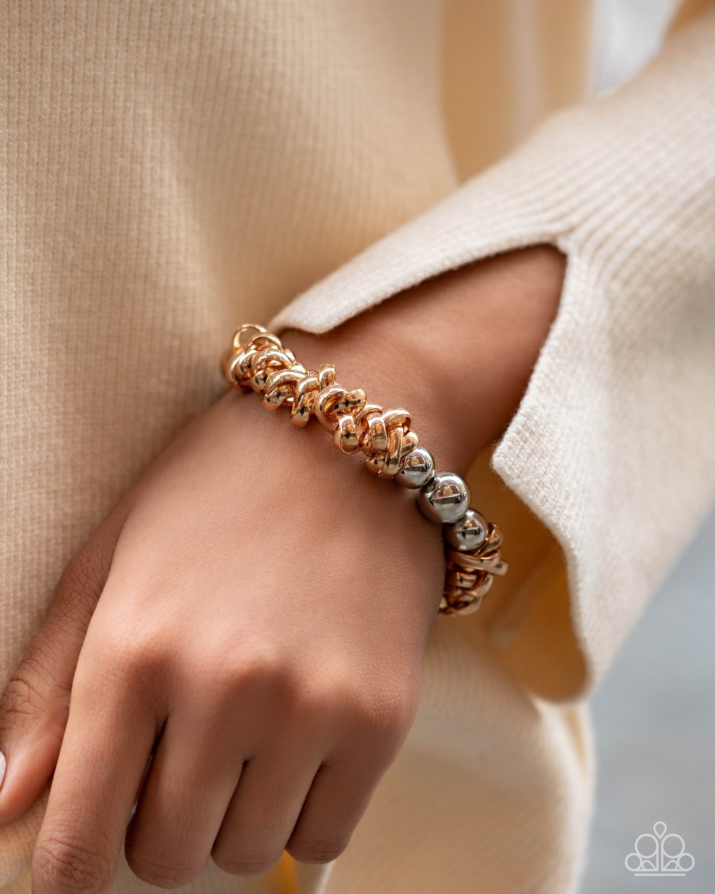 Rose gold and silver beaded bracelet on a wrist with a neutral background